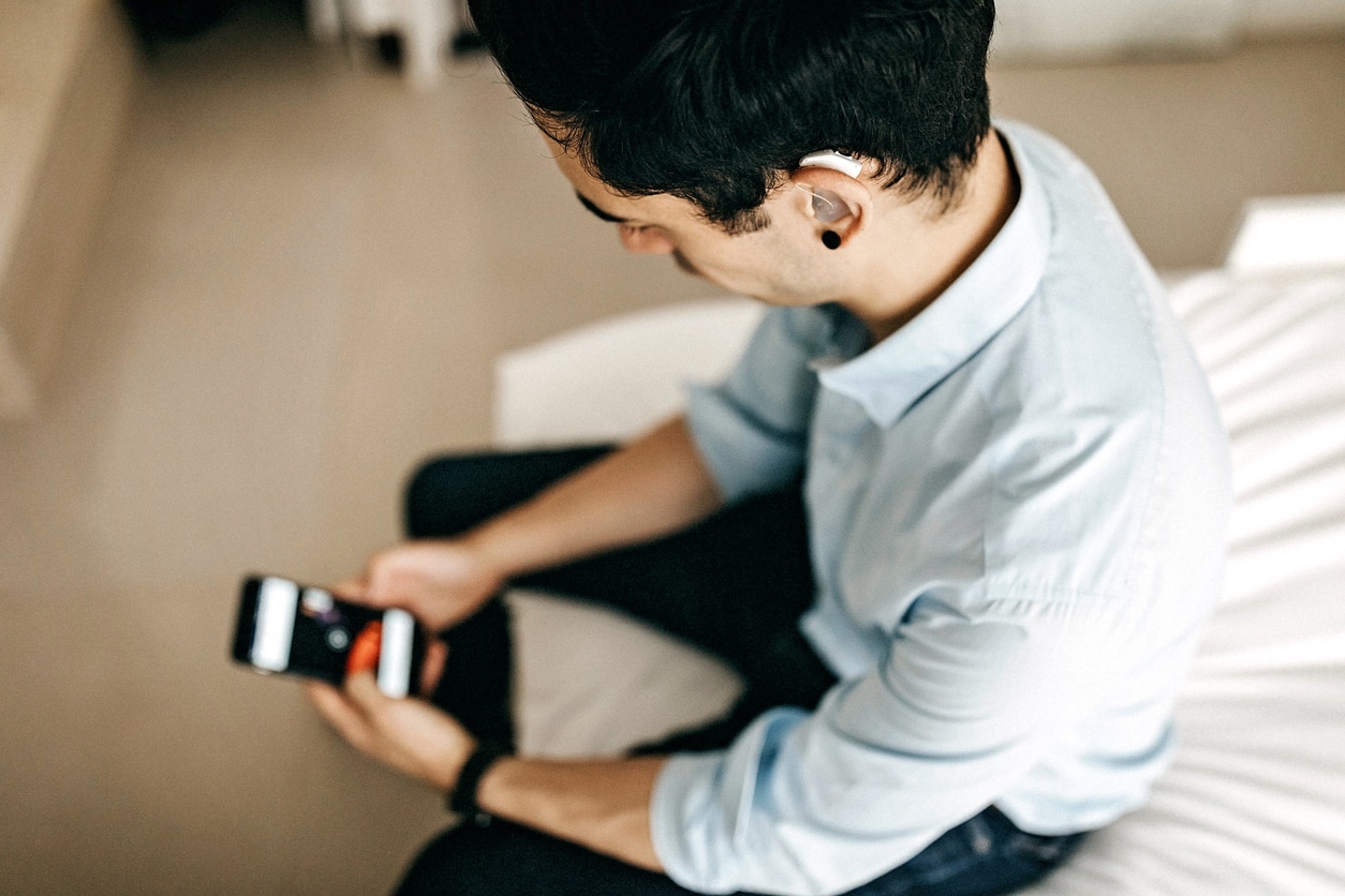 Relaxed Businessman Using Phone in Hotel Room who also has a hearing aid