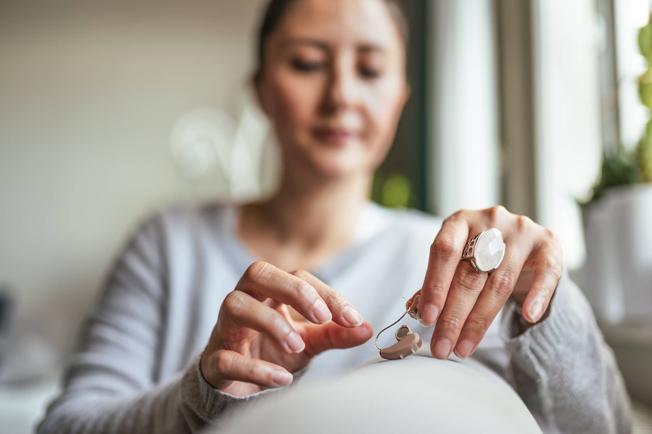 Young Adult Woman inserting battery into the Hearing Aid Young Adult Woman inserting battery into the Hearing Aid