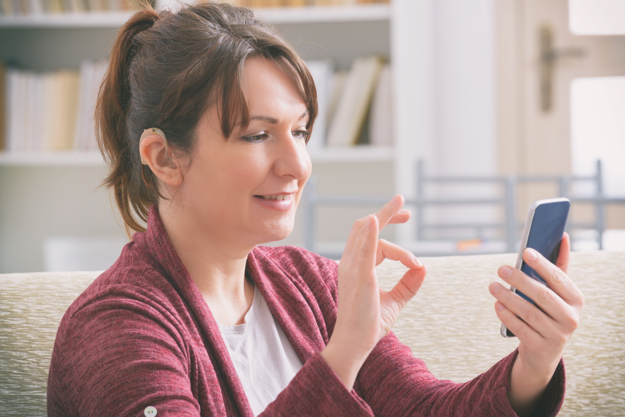 woman-hearing aid-smartphone Woman with hearing aid using her smartphone.